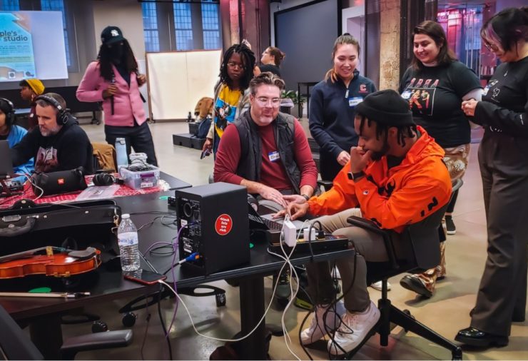 Students wearing headphones working on laptops to create beats, sounds, poetry, and more.