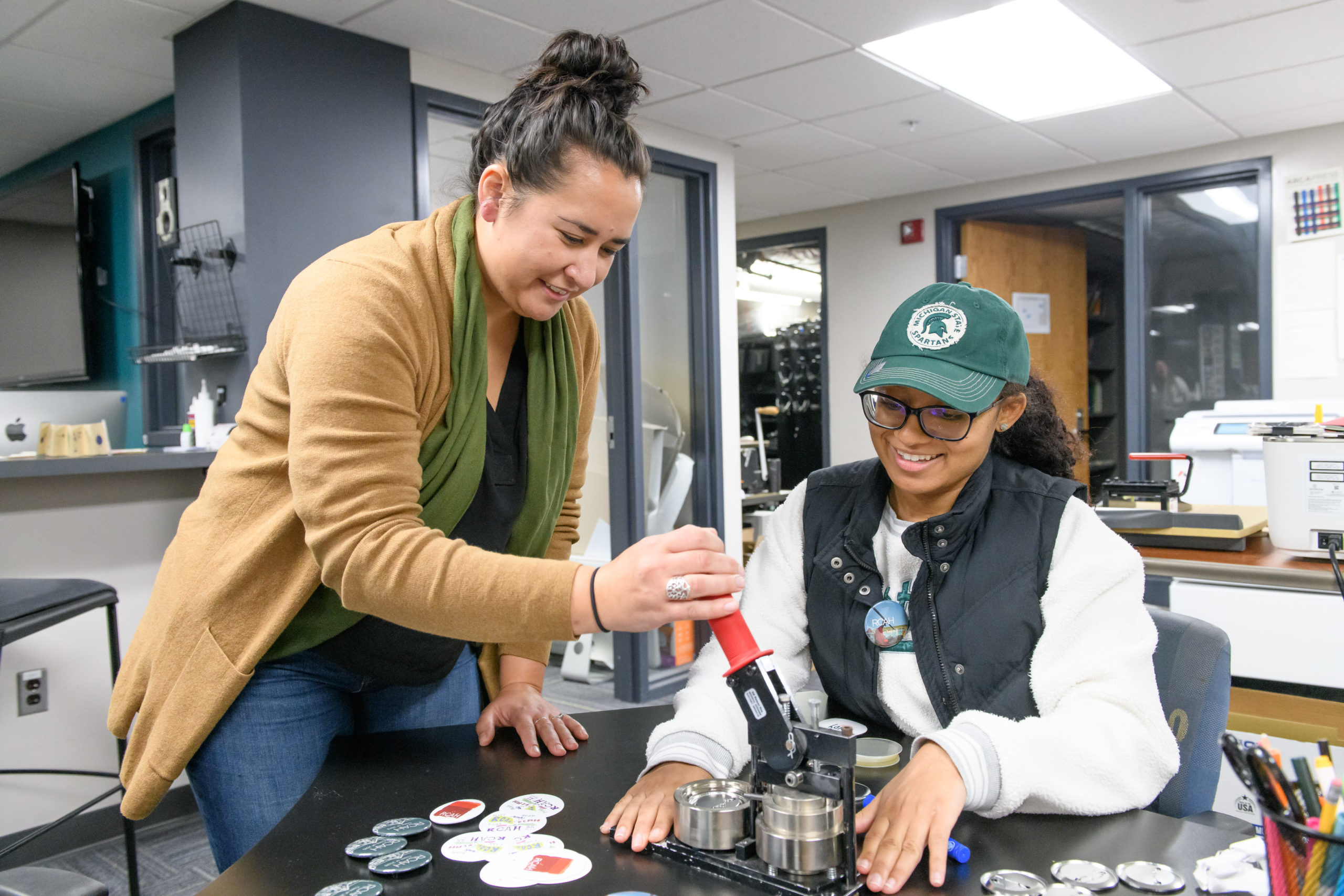 Two women using a button maker